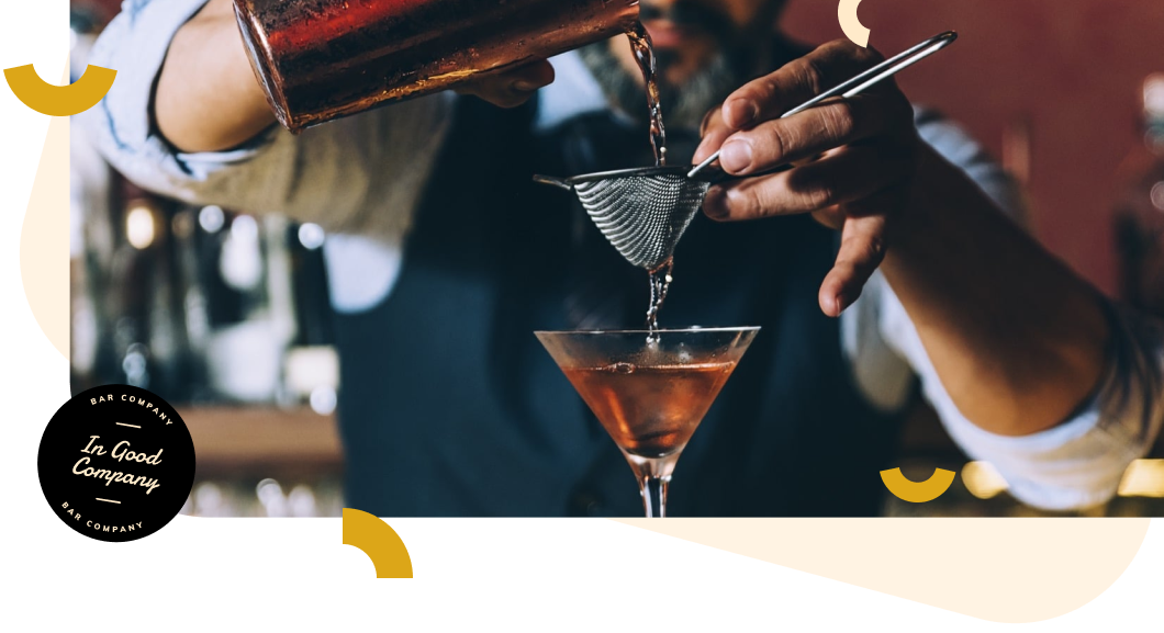 Barman zeeft een cocktail door een fijne zeef in een martiniglas achter de bar.