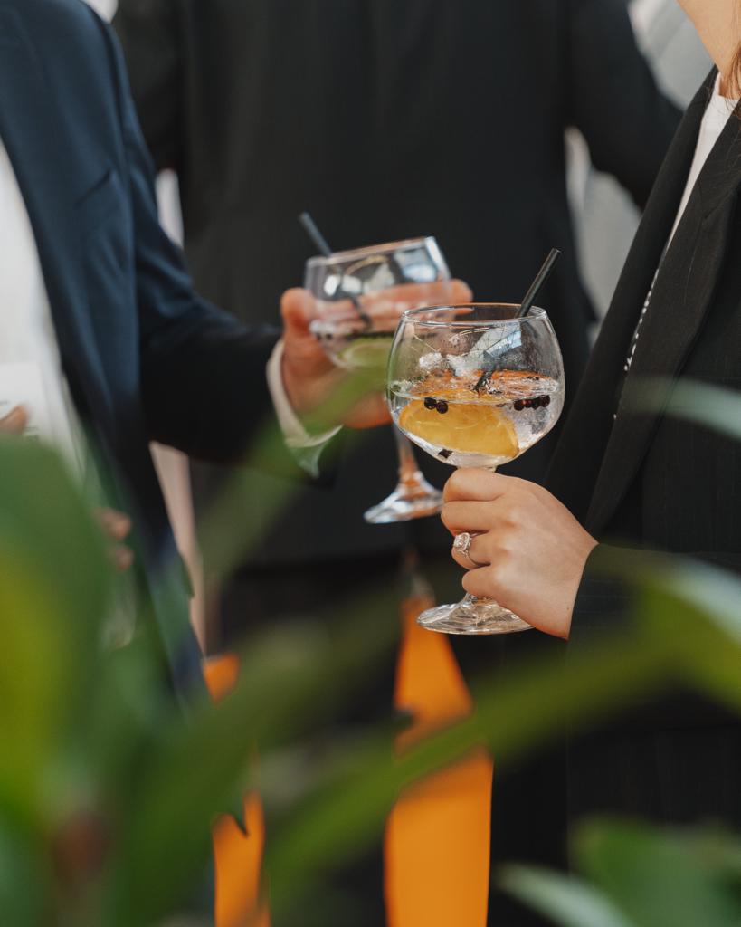 Twee mensen in zakelijke kleding proosten met gin-tonic cocktails met citroen en ijs in ballonglazen.