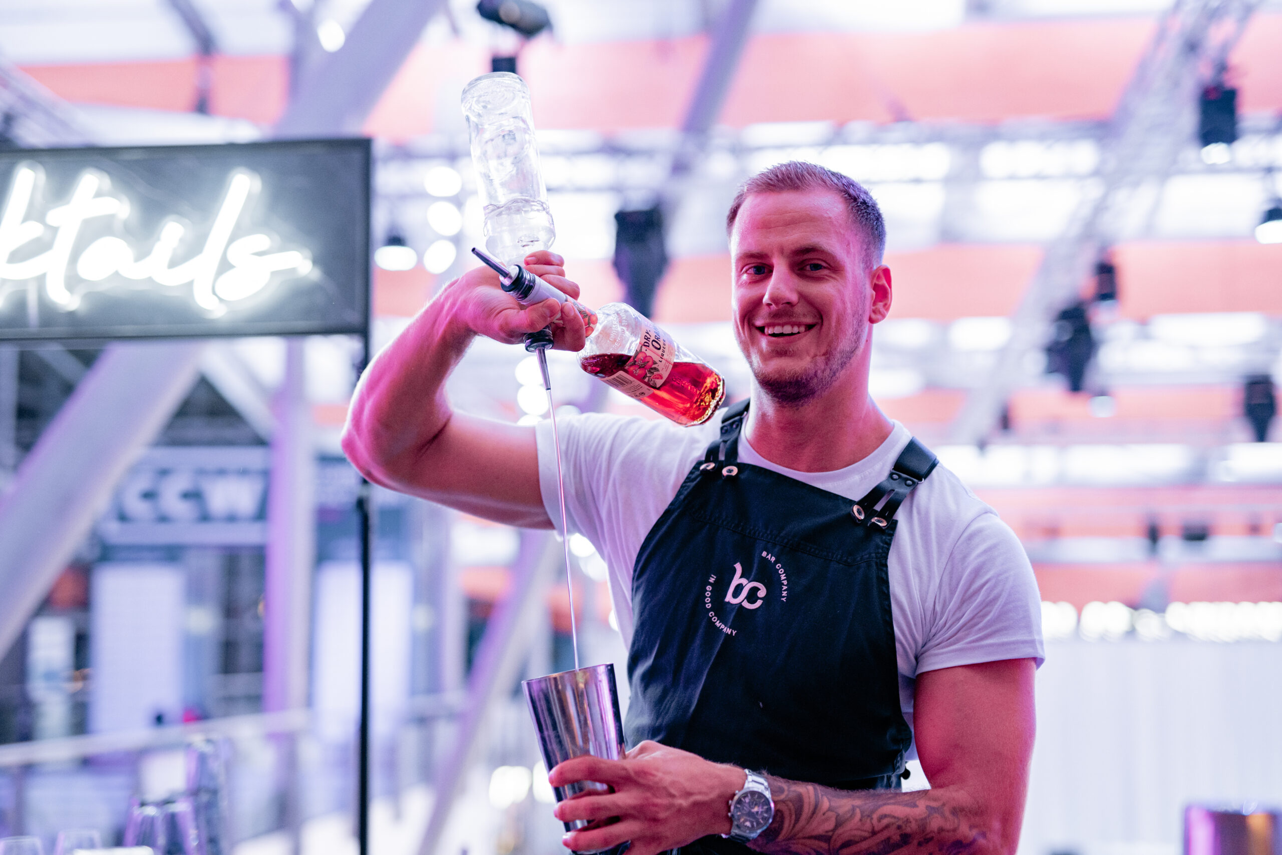 Bartender van Bar Company schenkt lachend uit twee flessen tegelijk in een shaker