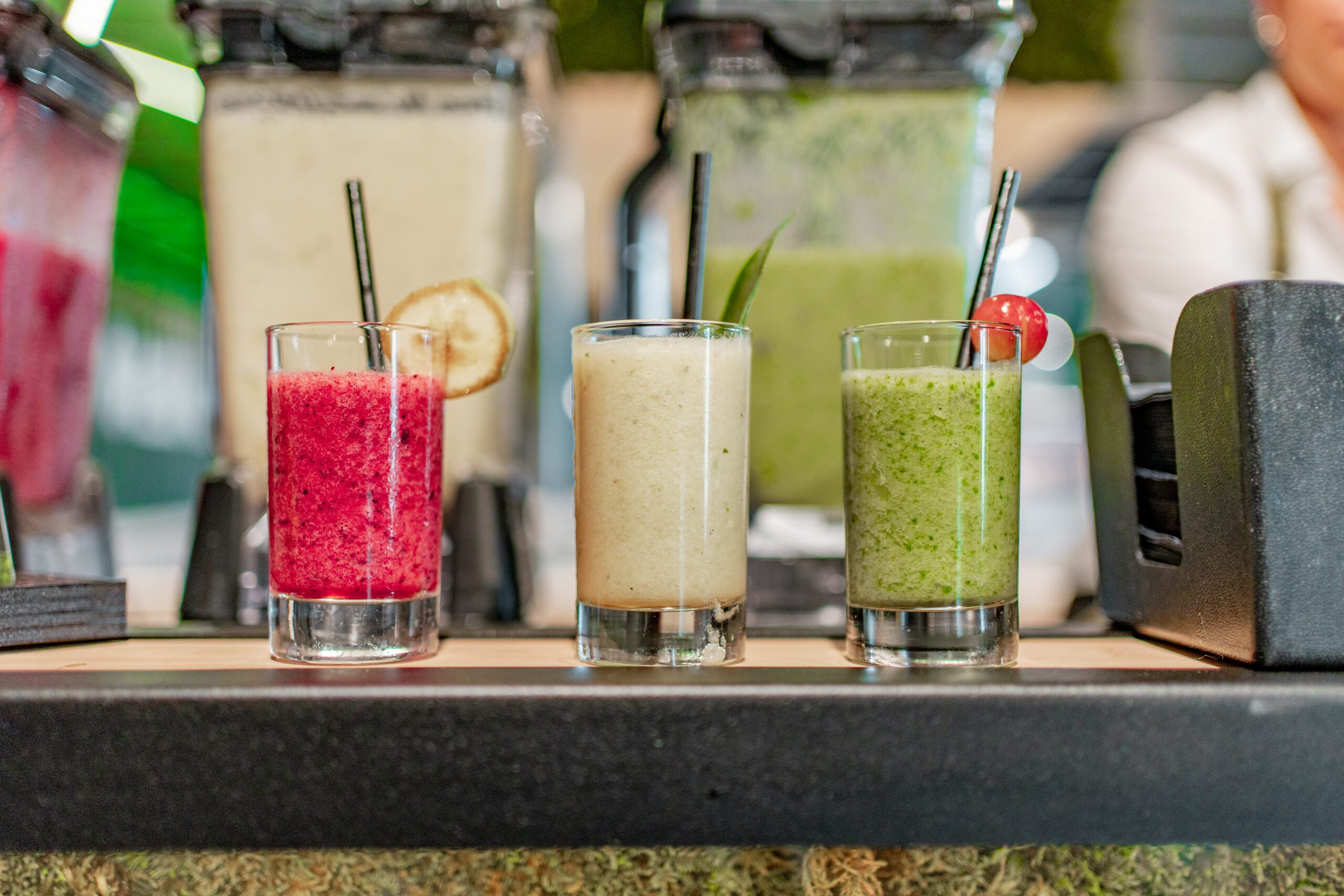 Drie shakes op een rij in roze, beige en groen, afgemaakt met een gedroogde schijf, blad en een druif.