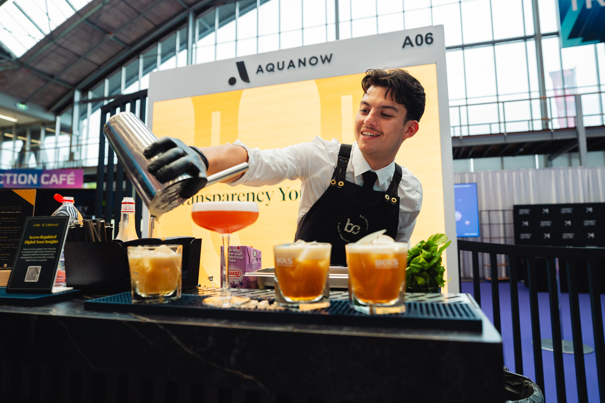 Bar Company bartender schenkt cocktails aan een beursstand met de branding van de klant op de achterwand