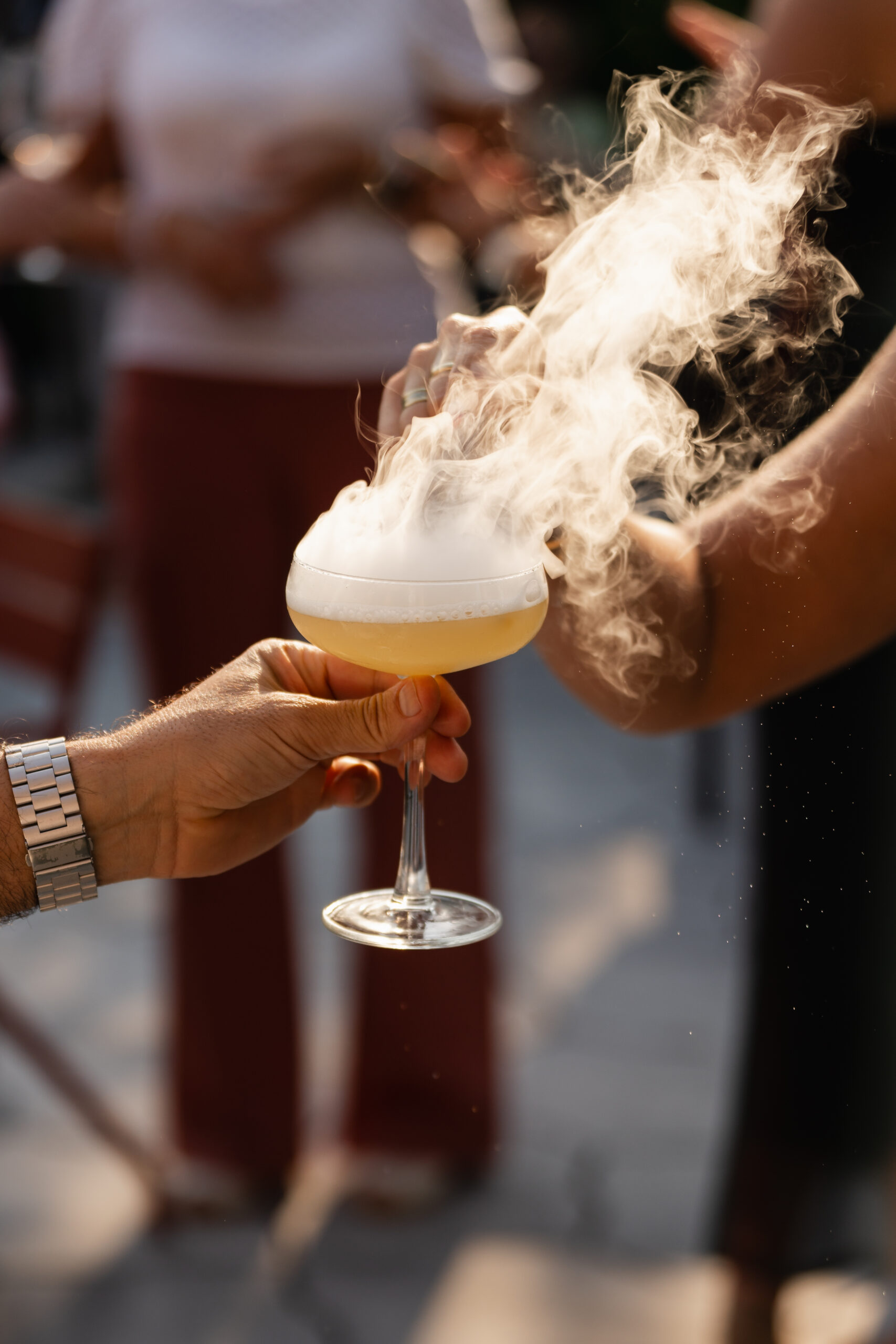Gast krijgt een gele cocktail aangereikt waar een dikke rookwolk uit het glas rolt