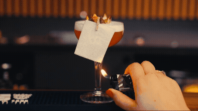 El camarero ilumina con un papel brillante el cóctel: un destello intenso en el momento de servirlo.