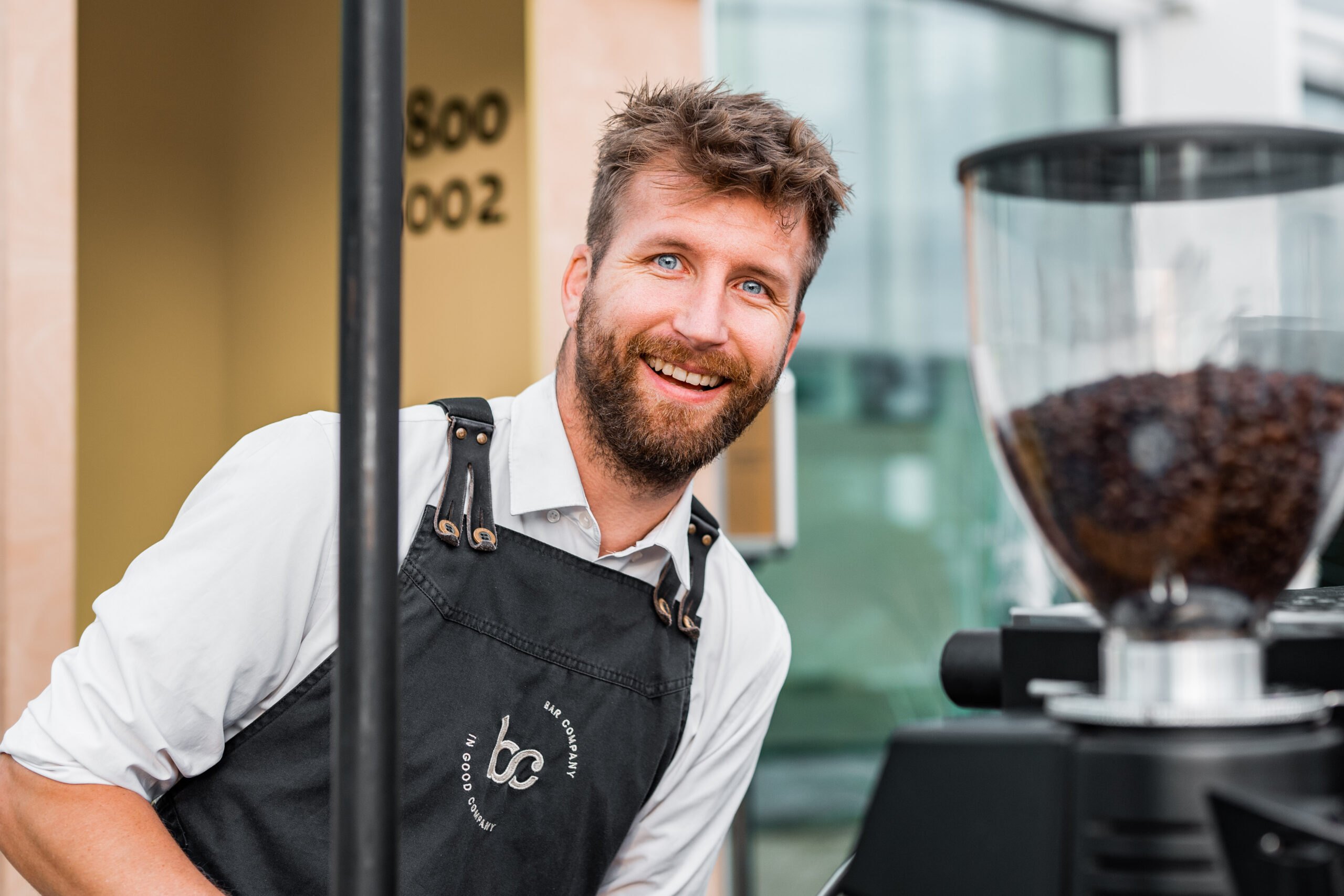 Barista van Bar Company lacht achter de koffiemachine