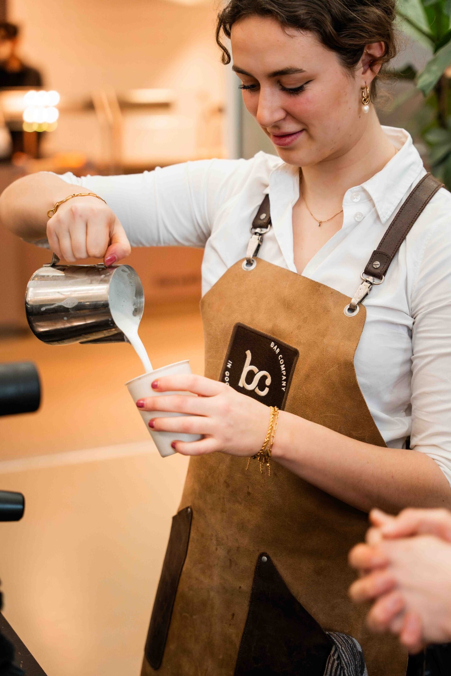 Barista van Bar Company schenkt melk in een cappuccino
